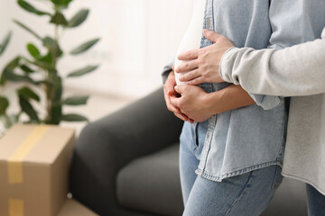 Pregnant woman and her husband in their new apartment, closeup. Space for text