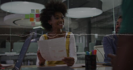 Image of data processing over african american woman reading a document to her colleagues