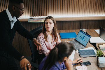 A focused team of diverse colleagues collaborates on a business project, discussing strategies at an office table.