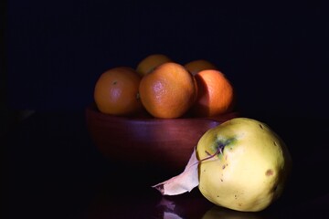 a fruit bowl with mandarins and a quince, low key photography