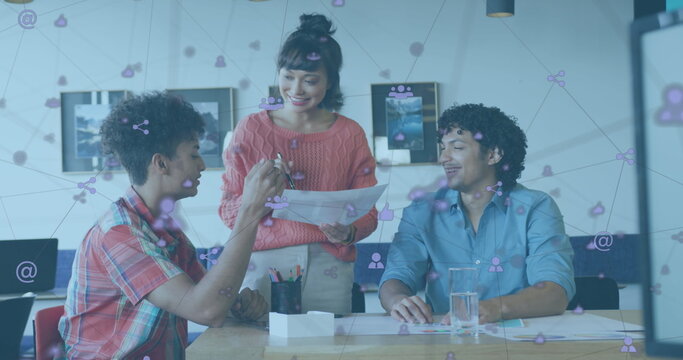 Image of icons connected with lines over diverse coworkers discussing reports on desk - Powered by Adobe