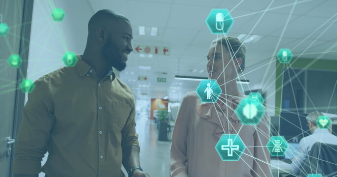 Image of connected icons globes, diverse coworkers discussing reports while walking in office