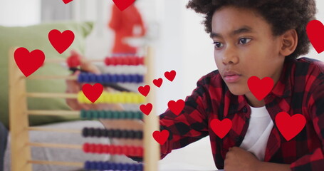 Image of social media heart icons over smiling biracial boy using abacus - Powered by Adobe