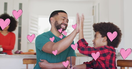 Image of social media heart icons over smiling biracial man and son high fiving