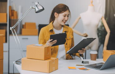 Asian SME business women use laptop computer checking customer order online shipping boxes at home....
