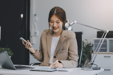 Portrait of a happy Asian businesswoman using mobile phone indoor, Asian businesswoman working in modern office.