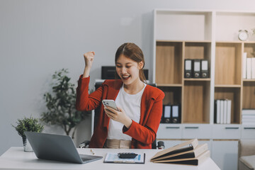Happy excited asian business woman in office working with mobile phone,Yes great job.