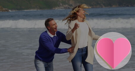 Image of heart icon over caucasian couple in love running on beach