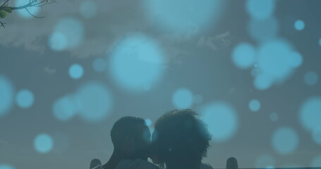 Image of light spots over biracial couple kissing