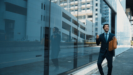 Skilled smart business man dancing with joyful while walking in glass wall. Project manger receive...