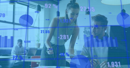 Image of multiple graphs and changing numbers over diverse coworkers discussing reports