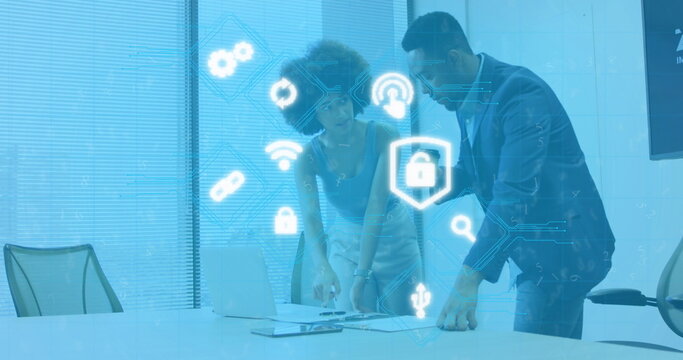 Image of illuminated icons over diverse coworkers discussing reports on laptop at office