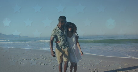 Image of stars over african american couple walking on beach
