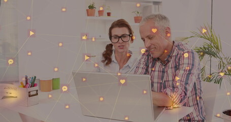 Network of digital icons against caucasian senior couple using laptop together at home
