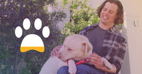 Image of paw icon over happy caucasian man with dog
