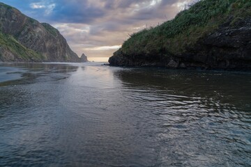 River flowing into the ocean at sunset. Anawhata, Auckland, New Zealand.
