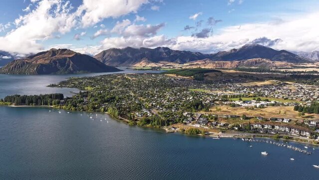 Stunning cloudscape of Wanaka settlement on big lake surrounded by mountains. New Zealand timelapse