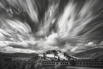Obraz premium Ancient Potala Palace against dynamic skies - The historic Potala Palace stands strong under the dramatic movement of the clouds in black and white