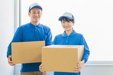 段ボールを持つ引越し業者・配達員の男女（引越し・配達・軽貨物ドライバー・宅配・配達員・宅急便）
