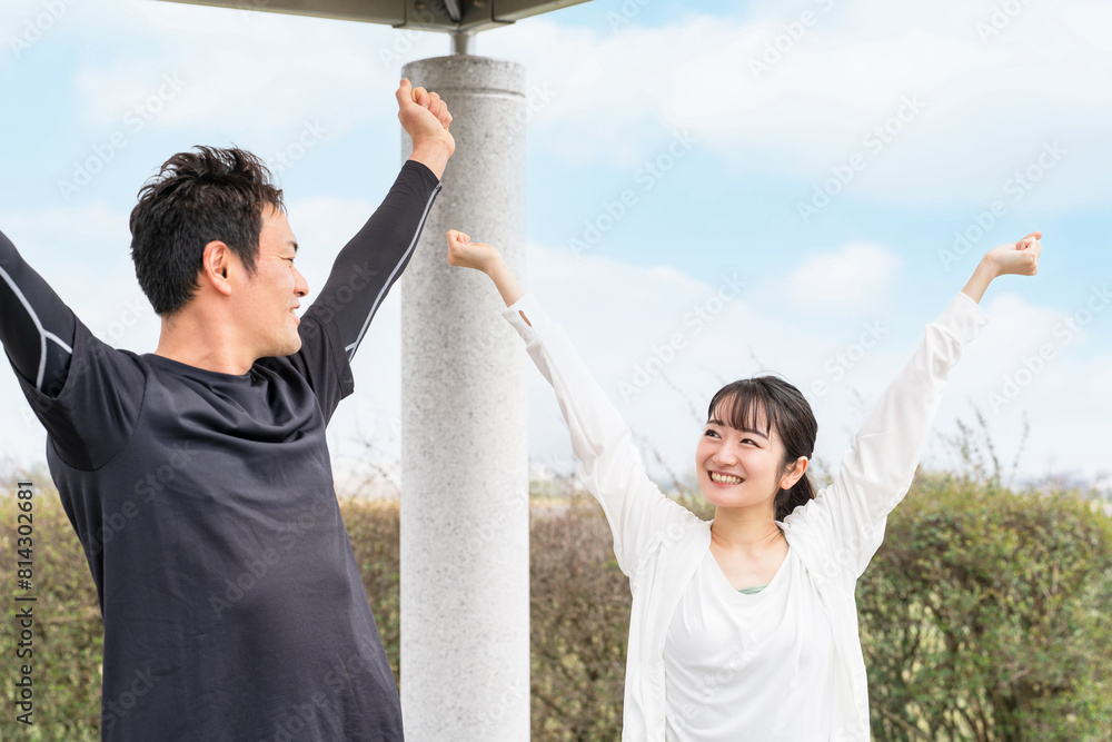 Wall mural 公園で準備運動・ウォーミングアップするスポーツウェアのアジア人男女
