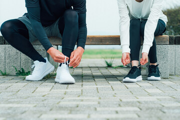 靴紐を結んで運動の準備をするアジア人の男女
