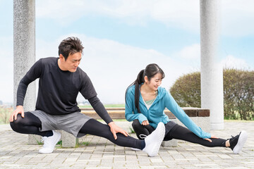 公園で準備運動・ウォーミングアップするスポーツウェアのアジア人男女
