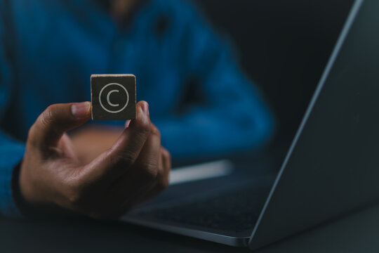 Person holding wooden block with copyright icon for author rights and patented intellectual property. copyleft trademark license. Copyright or patent concept.