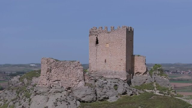 Ascending flight with a drone over the 9th century Oreja castle in the foreground starting with a blue sky background and discovering some crop fields through a camera turn Ontigola Toledo Spain