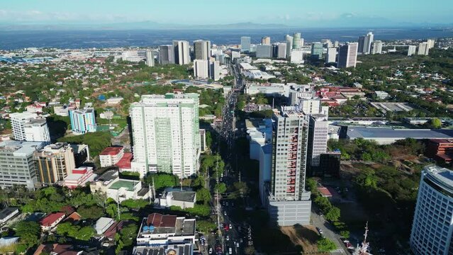 Aerial forward of bustling Philippine city with corporate buildings and busy highway in Alabang, Muntinlupa.