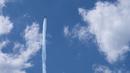 A military jet flies through a clear blue sky with minimal cloud cover.