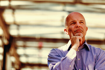 Pensive white-haired man, complex industrial background