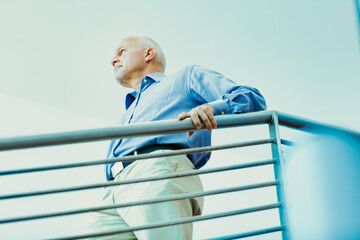 Thoughtful senior leans on railing, contemplating future