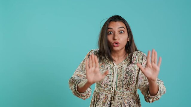Stern indian woman doing stop hand gesture sign, complaining. Authoritative person doing firm halt sign gesturing, wishing to end concept, isolated over studio background, camera A