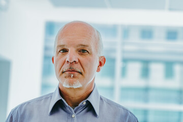 Older man stands contemplatively before large window