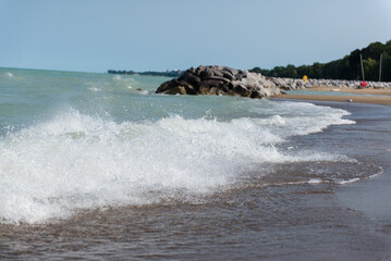 Beach near Lake Michigan. Rough waves. A pile of large stones near the lake and the beach.