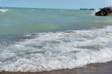 Lake Michigan. Rough waves. A pile of large stones near the lake and the beach.