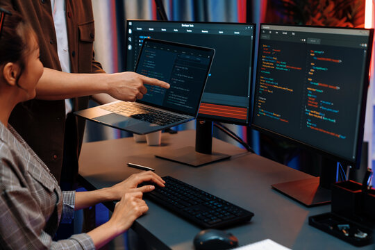 Serious of IT developers discussing intelligent website development coder system running data online two screens with laptop showing information network at neon light room at modern office. Infobahn.