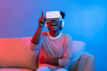 Surprised African American woman watching film through VR in fantastic 3D cartoon movie technology...
