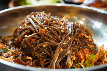 buckwheat noodles with spicy sauce on a stainless steel plate, close up