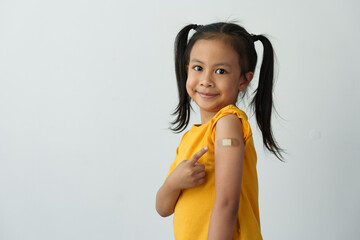 Little girl shows her arm after getting the vaccine, with a bandage on to protect against germs,...