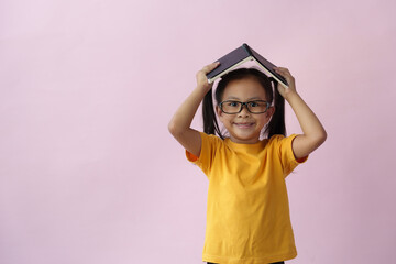 Child wearing glasses holding a notebook Note paper in a notebook Dreamy young girl on pink background space education concept learning.