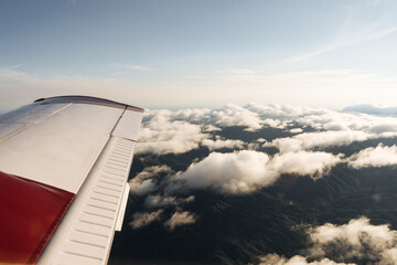 Fototapeta na wymiar A small plane flying over Costa Rica, view from the window with clouds at sunset