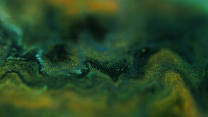 Blur marble texture. Glitter paint flow. Defocused green gold yellow black color shimmering ink mix...