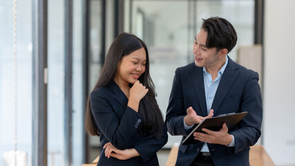 Two engaged business professionals review and discuss documents in office.