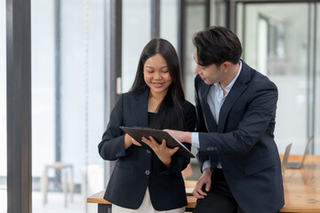 Two engaged business professionals review and discuss documents in office.