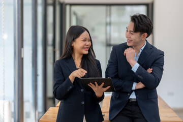 Fototapeta premium Two engaged business professionals review and discuss documents in office.
