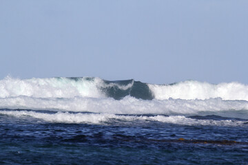 Close up of breaking ocean wave under a clear blue sky