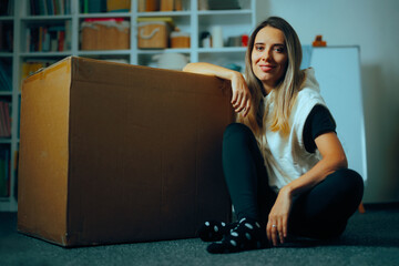 Woman Sitting Next to a Big Delivery Box in the Living Room. Happy customer receiving her online...