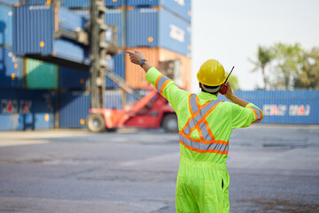 back view worker or engineer using walkie talkie and showing gesture to crane car in containers warehouse storage