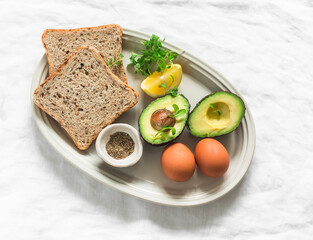 Ingredients for making a wholegrain sandwich with avocado, scrambled eggs and microgreens on a light background, top view